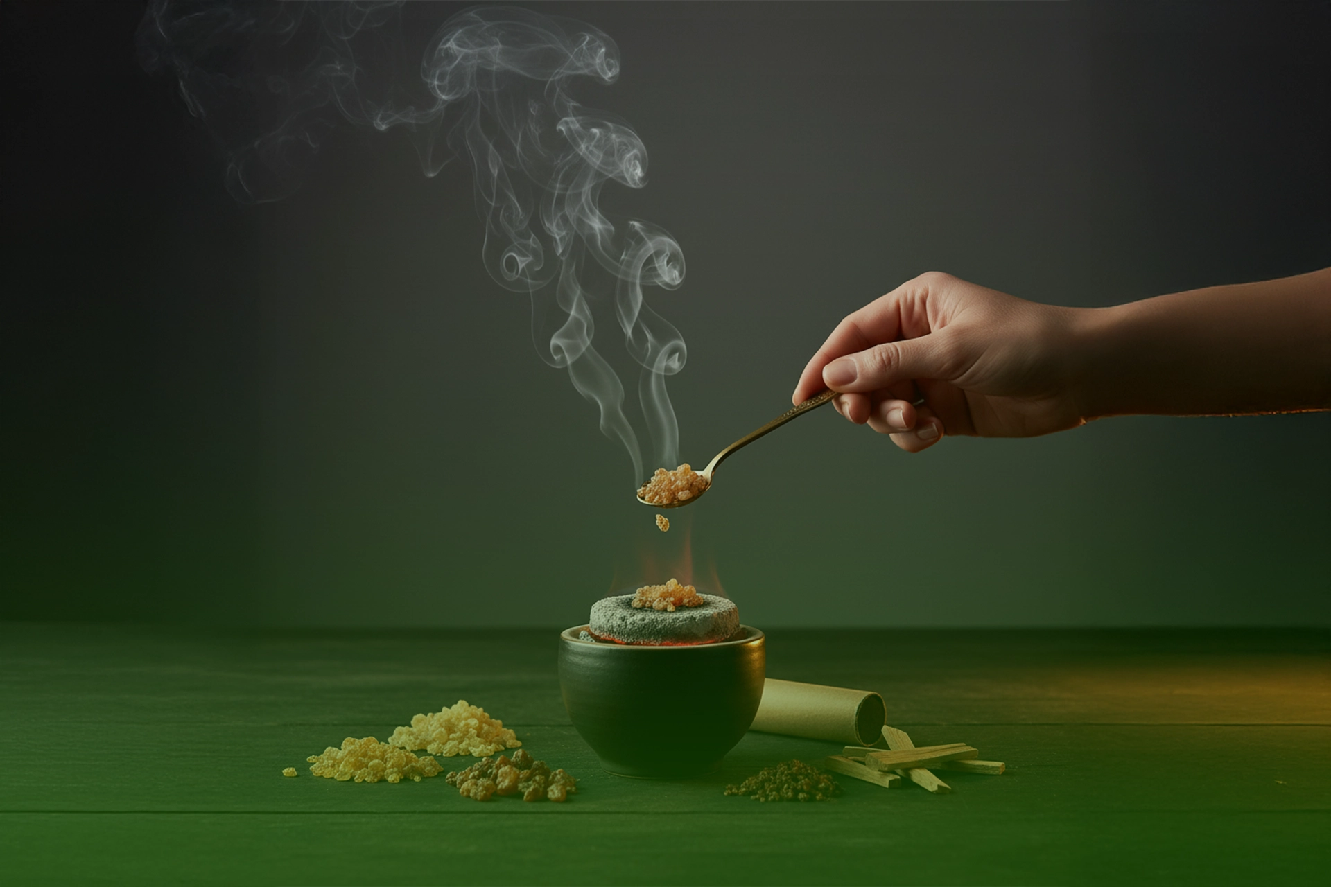 Mano colocando granos de resina sobre un carbón vegetal encendido en un quemador, con humo aromático elevándose.
